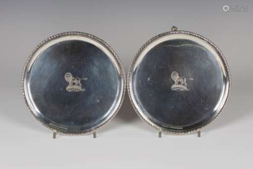 A pair of George III silver circular salvers with gadrooned rims, each engraved with a lion crest,