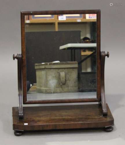 An early Victorian mahogany swing frame mirror, raised on split scroll supports and a bowfront base,