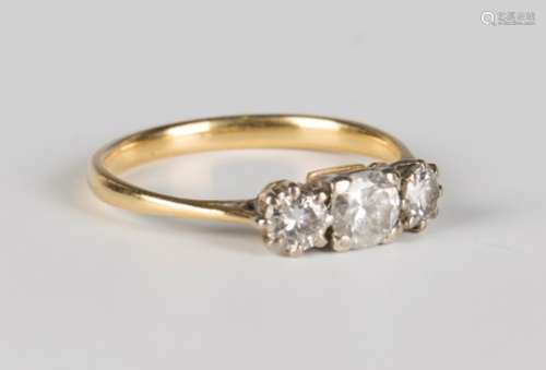 A gold and diamond three stone ring, claw set with a row of circular cut diamonds with the principal