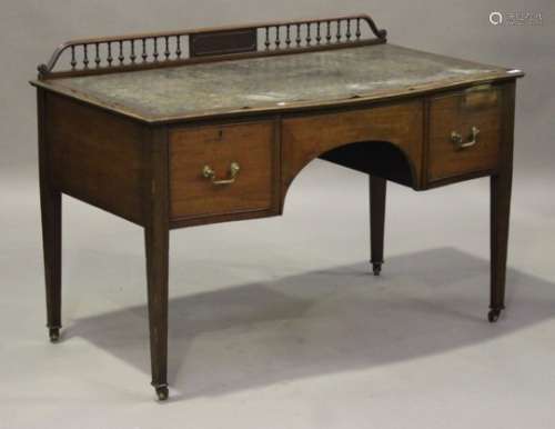 An Edwardian mahogany serpentine fronted kneehole writing table, the turned spindle gallery above