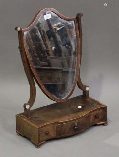 A George III mahogany swing frame mirror, the serpentine base with crossbanded borders and fitted