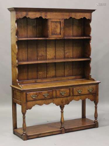 A modern reproduction oak dresser, the shelf back above three drawers and an open shelf, on turned