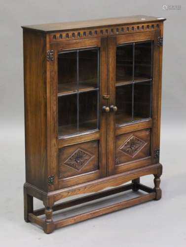 A mid-20th century oak glazed bookcase with carved decoration, on turned and block legs, height