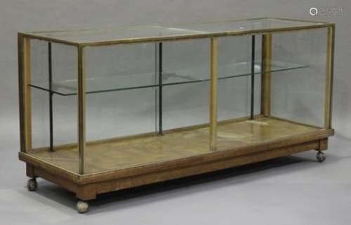 An Edwardian oak and brass mounted shop display counter, the glazed sliding doors enclosing glass