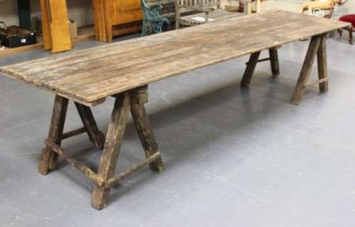 A large early 20th century French pine trestle table, the rectangular plank top raised on a pair