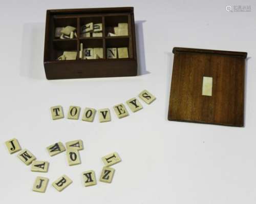 A late Victorian mahogany cased bone alphabet set, each tile inscribed in black ink, the sliding lid