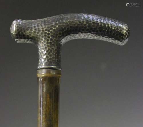 An early 20th century bamboo walking cane, the white metal handle with overall hammered
