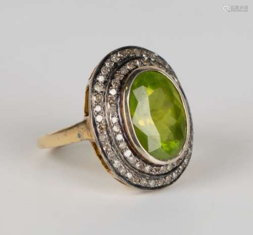 A gold peridot and diamond cluster ring, collet set with an oval cut peridot within a two row
