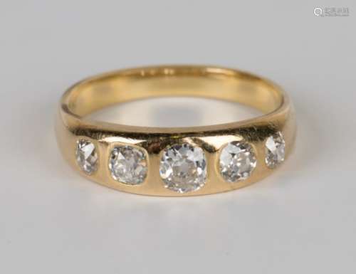 A gold and diamond five stone ring, gypsy set with a row of cushion shaped diamonds graduating in