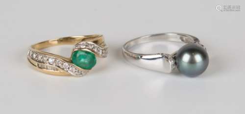 A 9ct gold ring, mounted with an oval cut emerald between diamond set serpentine shoulders,