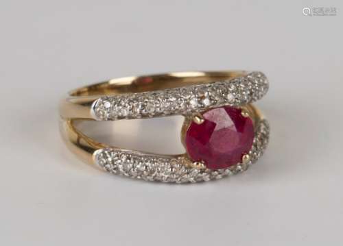 A 9ct gold ring, claw set with an oval cut ruby between circular cut diamond set two row sides in an