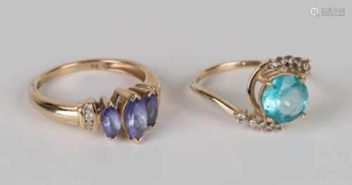 A 9ct gold ring, claw set with a circular cut blue stone between diamond set serpentine shoulders,