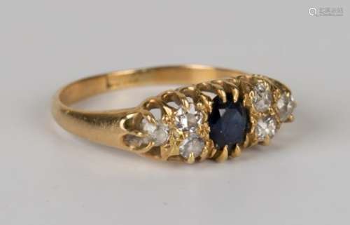 A gold, sapphire and diamond ring, claw set with an oval cut sapphire between two groups of three