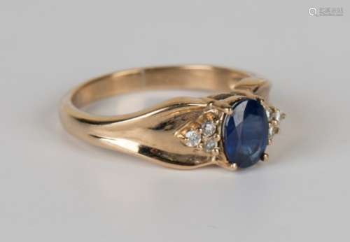A 9ct gold ring, claw set with an oval cut sapphire between circular cut diamond set three stone