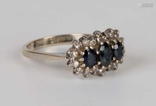 An 18ct white gold, sapphire and diamond ring, claw set with three oval cut sapphires within a