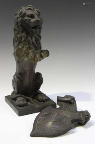 A 19th century carved oak model of an heraldic lion, seated on its hind legs and holding a shield,