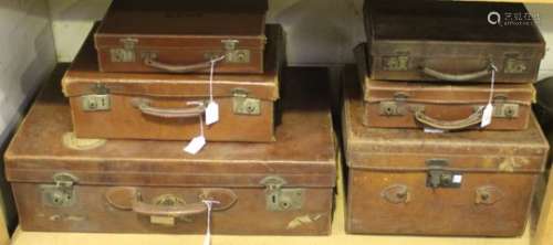 A group of early 20th century brown leather luggage, comprising five various suitcases and a hat