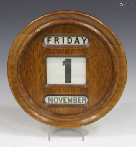 A mid-20th century mahogany and oak circular perpetual wall calendar, diameter 32cm.Buyer’s