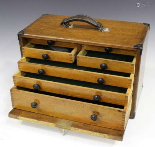 An early/mid-20th century teak tool cabinet by 'M & W', the top with carrying handle, the