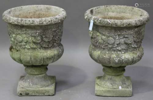 A pair of 20th century cast composition stone garden urns, the half-reeded bodies cast with flowers,