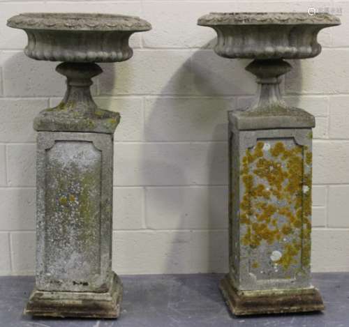 A pair of late 20th century cast composition stone garden urns on stands, each reeded circular