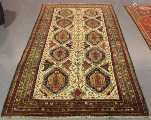 An Afghan long rug, mid-20th century, the ivory field with two columns of hooked guls and stylised