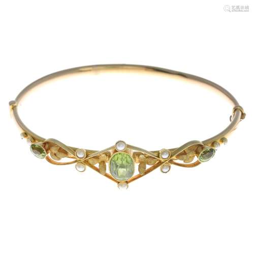An early 20th century 15ct gold peridot and split pearl bangle.