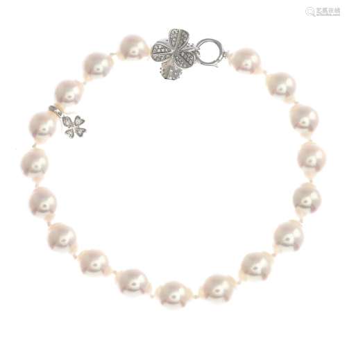 A cultured pearl bracelet with diamond clasp, suspending a diamond four leaf clover charm.