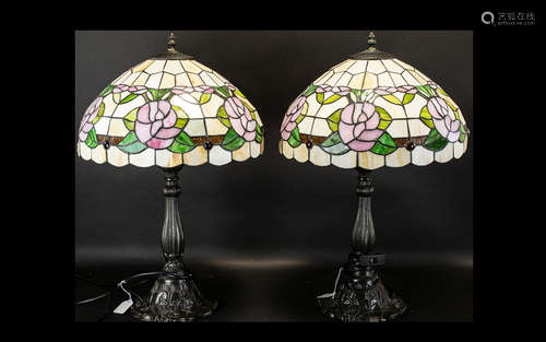 A Pair Of Reproduction Tiffany Style Table Lamps each raised on bronzed metal base with shaped