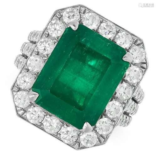 A 7.69 CARAT EMERALD AND DIAMOND CLUSTER RING set with