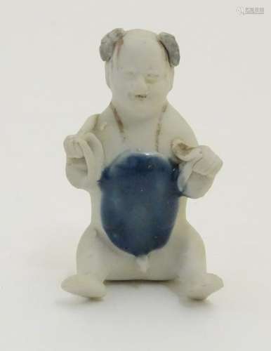 An 18thC Chinese porcelain figure of a naked boy seated