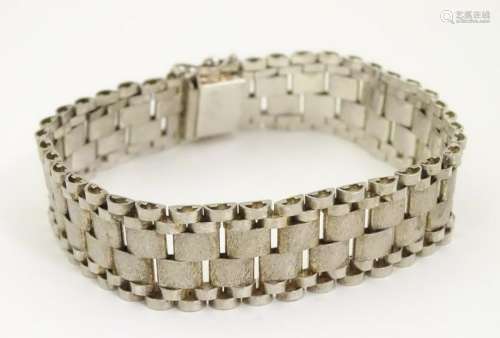 A silver bracelet of wide link strap form
