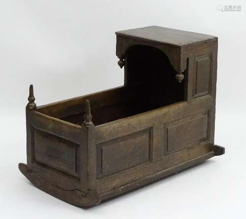 An 18thC oak crib with an overhanging hood and