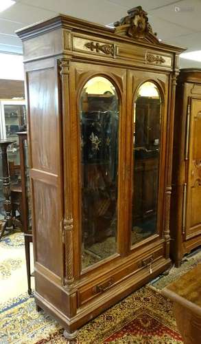 A late 19thC walnut armoire with a carved pediment