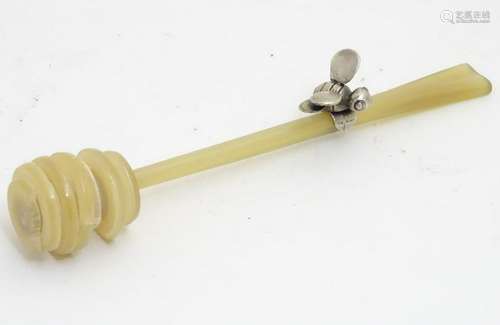 A celluloid honey drizzler / dipper with a silver honey