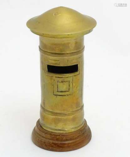 A money box in the form of a brass pillar post box on a