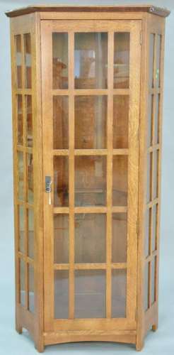 Stickley oak corner cabinet with four glass shelves.