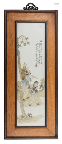 A Chinese polychrome decorated porcelain plaque in a wooden frame, decorated with a woodcutter and a boy, returning with their yield, with a signed text, 39 x 94 cm (frame)