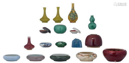 A collection of smaller Chinese porcelain items, consisting of a flambé glazed seal paste box, Kangxi marked and probably period, a seal paste box with text on the inside of the cover, probably 18thC, three monochrome glazed smaller bottles: two of them with fish roe crackled lemon glazed and one bottle with sang the boeuf glaze, one miniature vase with sancai relief decoration, eight brush washers: one brush washer green monochrome and one brush washer celadon glazed, two items with tea dust glaze and a Kangxi mark, 19thC, one with robin's egg glaze, one blue and copper red glazed, with a Kangxi mark, maybe period, one with a crackled relief decoration, a green monochrome glazed miniature vase, a sang de boeuf glazed bowl and a peach bloom glazed jar,  H 3 - 13 - ø 6,5 - 15,5 cm