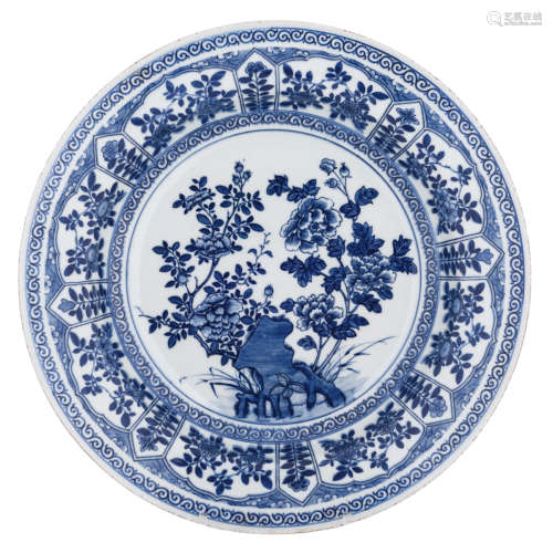 A Chinese blue and white charger, the centre decorated with a scholar's rock and peonies and encircled with flower panels, to the reverse a mountainous landscape, marked Kangxi, H 6 - ø 37,5 cm