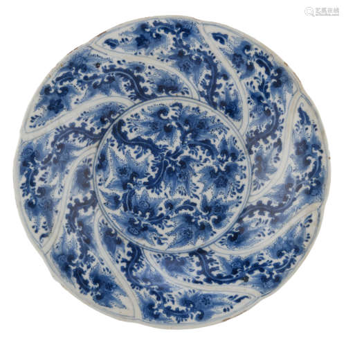 A Chinese Kangxi blue and white export porcelain soup plate, the well decorated with leafy tendrils and encircled by a swirled lobed rim, split by panels of a repeating foliage design, with a Kangxi symbol mark, H 4,4 - ø 27 cm