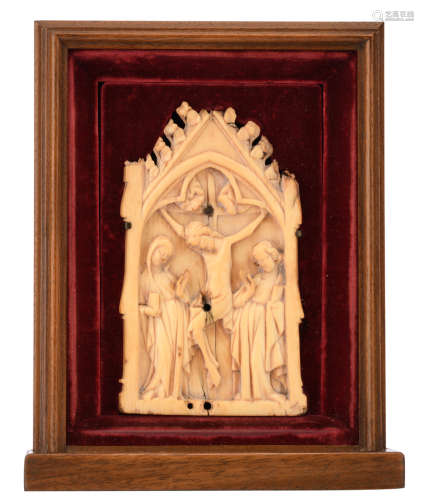 An alto relievo carved chapel-like shaped ivory plaque depicting the crucified Christ flanked by the Holy Mother and Saint John, the scene set beneath a gothic trefoil arch, probably French - 14th century; 20thC mounted in a red velvet-covered niche that is surrounded by a mahogany frame, H 13,4 - W 7,9 cmAdded expertise report according to CITES legislation. For European Community use only.