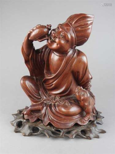 A Chinese carved boxwood figure of a cross-legged monk drinking from a ewer with a tiger cub at