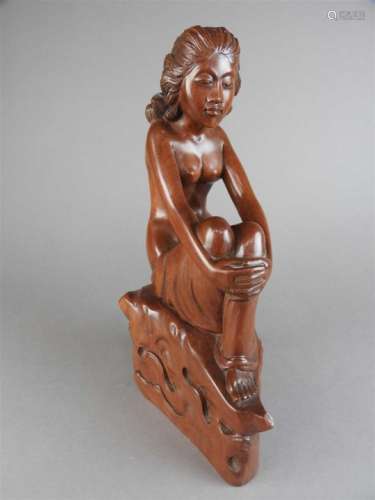 A Chinese carved boxwood figure of a seated semi-nude woman, she sits cross-legged with her arms
