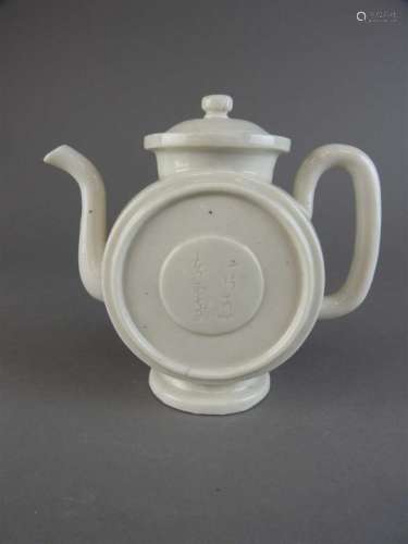 A Chinese porcelain teapot, Dehua, Qing Dynasty, of drum form, the centre of each side incised