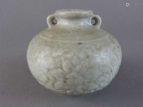 A Chinese celadon two handled squat globular jar, probably Ming Dynasty, carved with a bold
