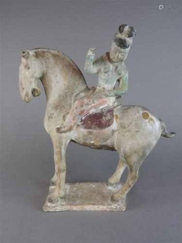 A painted pottery horse and rider in Tang style, the rider leaning over to the left and seated on