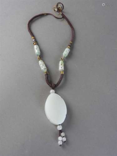 A Chinese white jade pendant of oval quatrelobed form carved to one side with a boy with hand fan