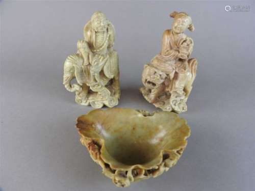 A Chinese soapstone figure holding a basket of peaches and seated upon a lion dog, Qing Dynasty,