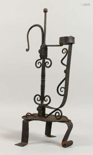 AN ORNATE WROUGHT IRON CANDLE HOLDER, on three feet.